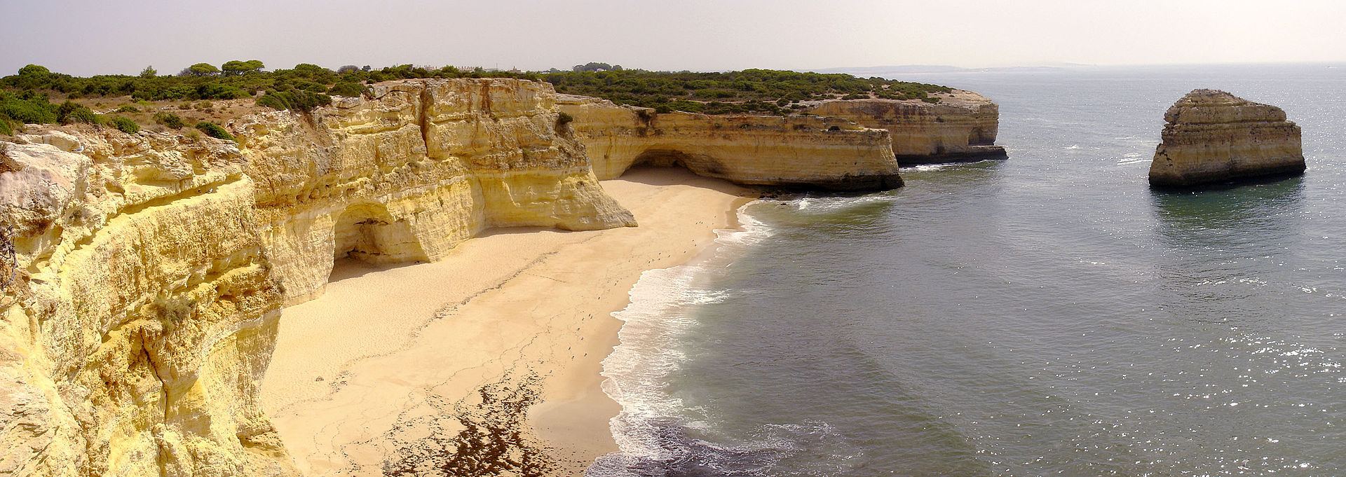 Praia da Marinha quase deserta, com o mar calmo e as falésias ao fundo