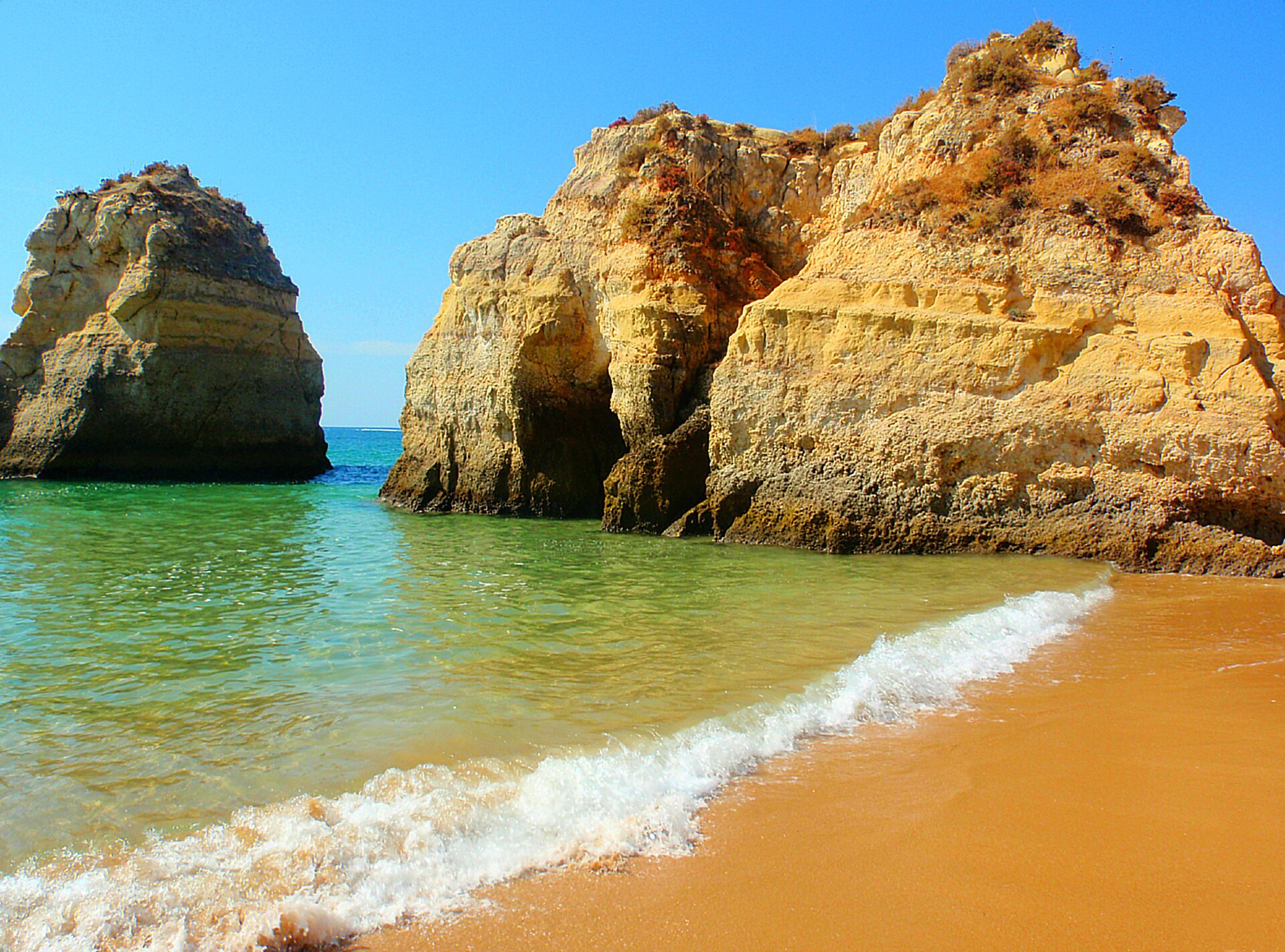 Vista da Praia dos Três Irmãos, com o areal e as formações rochosas junto ao mar, em Alvor